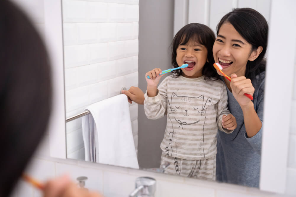 happy attractive mom and kid brushing their teeth together