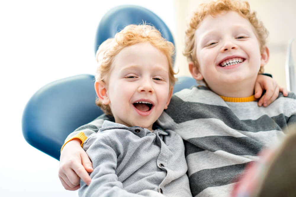 happy young brothers sitting on the dental chair